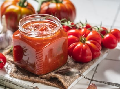 A shot of a jar of homemade sauce made from fresh red fruits, showcasing tomato varieties for making salsa